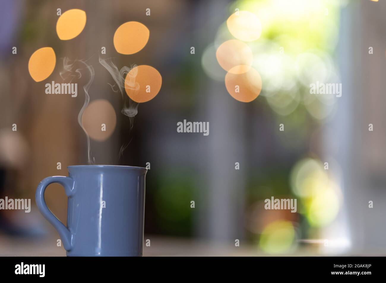 Selective focus of steam coming out of a mug against bokeh light background Stock Photo