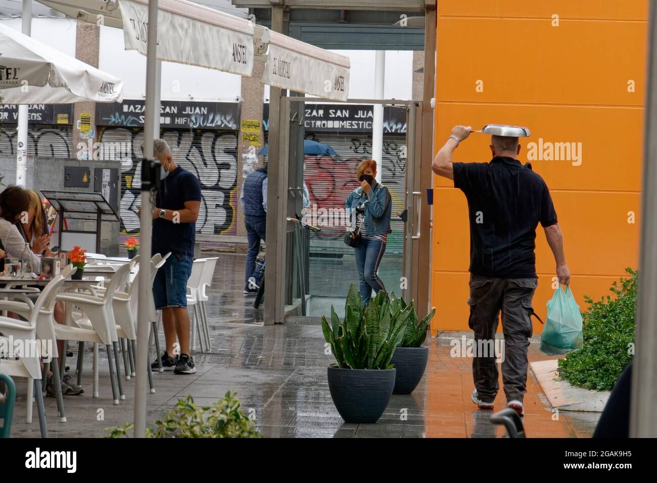 Regen in Malaga, Mann mit Bratpfanne als Regenschutz, Altstadt Malaga, Costa del Sol, Provinz Malaga, Andalusien, Spanien, Europa, Stock Photo