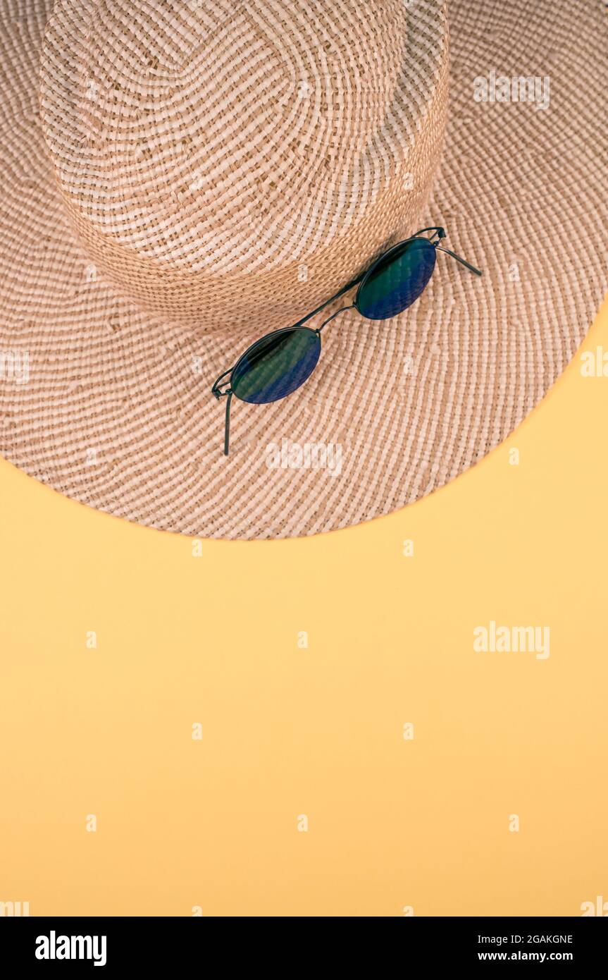Vertical shot of a straw hat and sunglasses on a yellow surface Stock ...