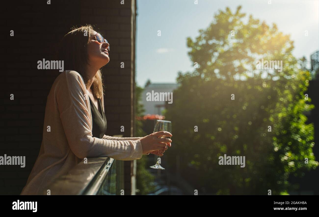 Woman in sunglasses enjoying white wine on the balcony Stock Photo - Alamy