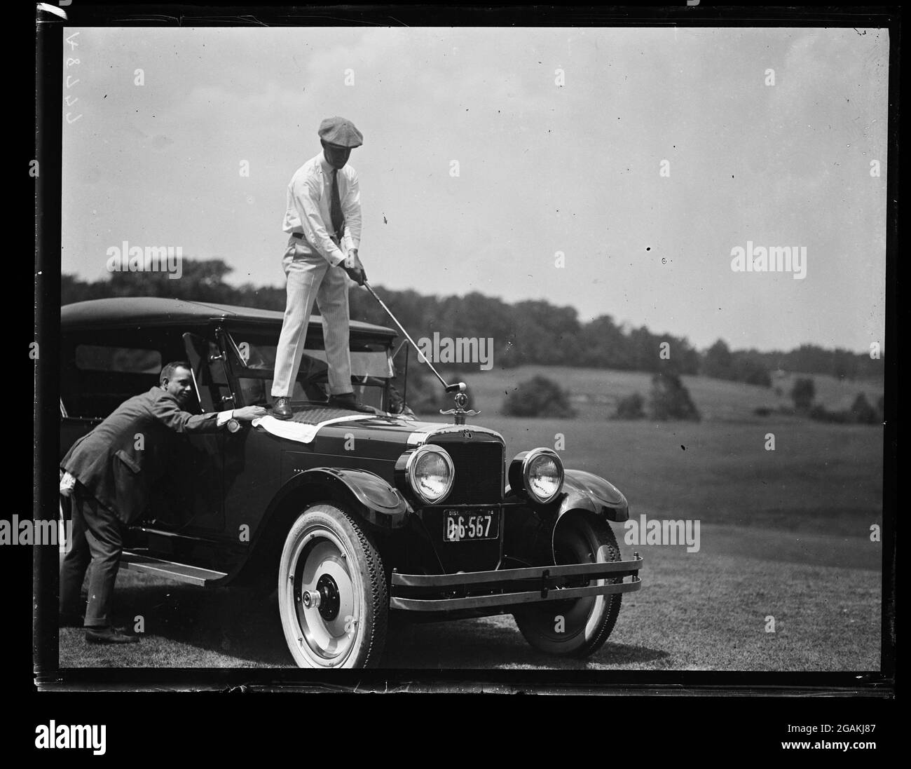 A photo of a stunt golf shot - man teeing off from atop an automobile, Washington, DC,1924. (Photo by Harris & Ewing/RBM Vintage Images) Stock Photo