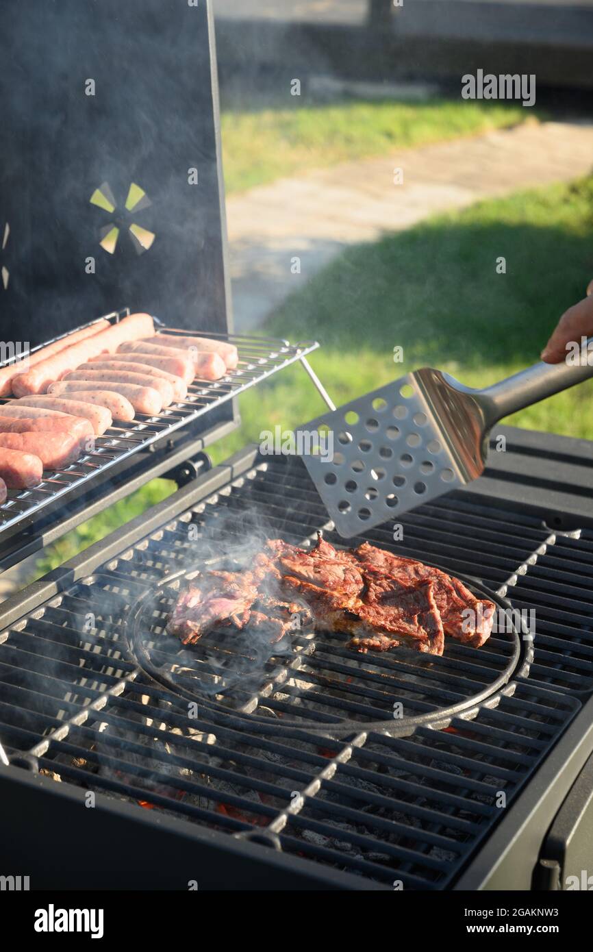 Beef steaks and sausages on grill. Barbecue backyard party. Outdoors. Stock Photo