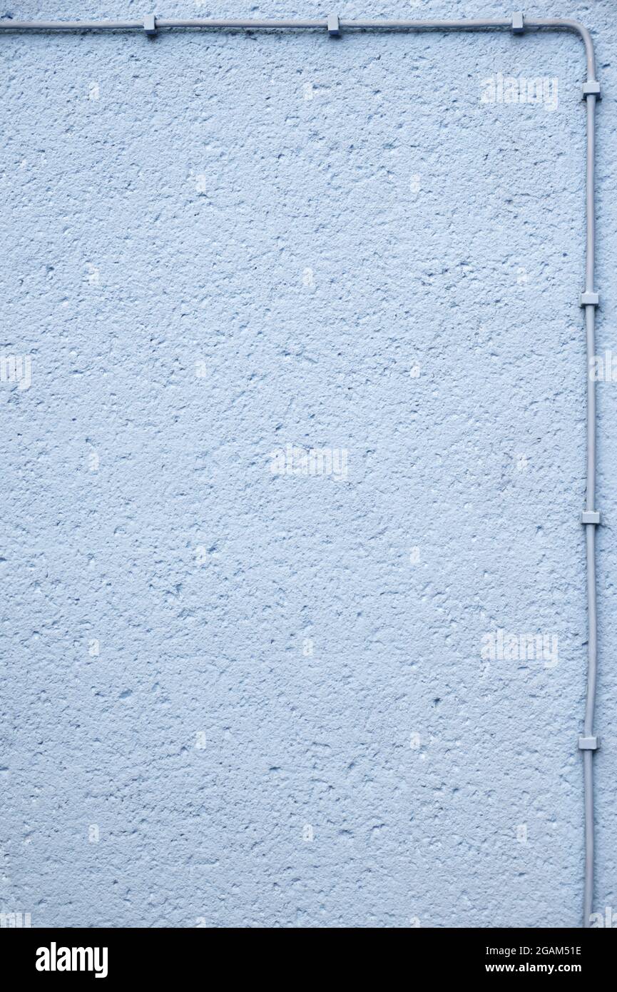 Light blue rough plastered wall, framed with electrical cable; grunge background with copy space Stock Photo
