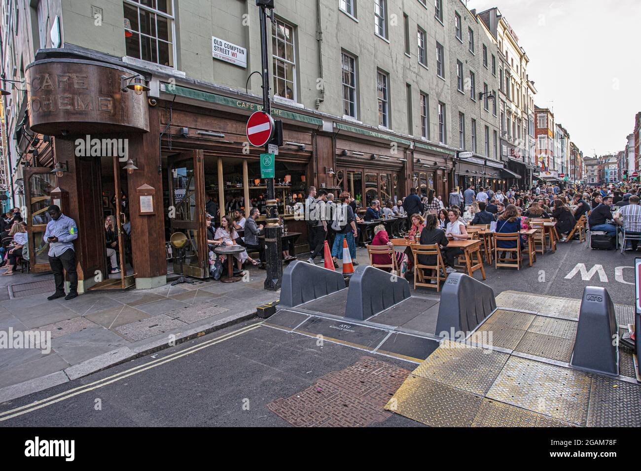 People celebrating 'freedom day' ending over a year of COVID-19 lockdown restrictions in England people drinking on tables placed outside on  Old Comp Stock Photo