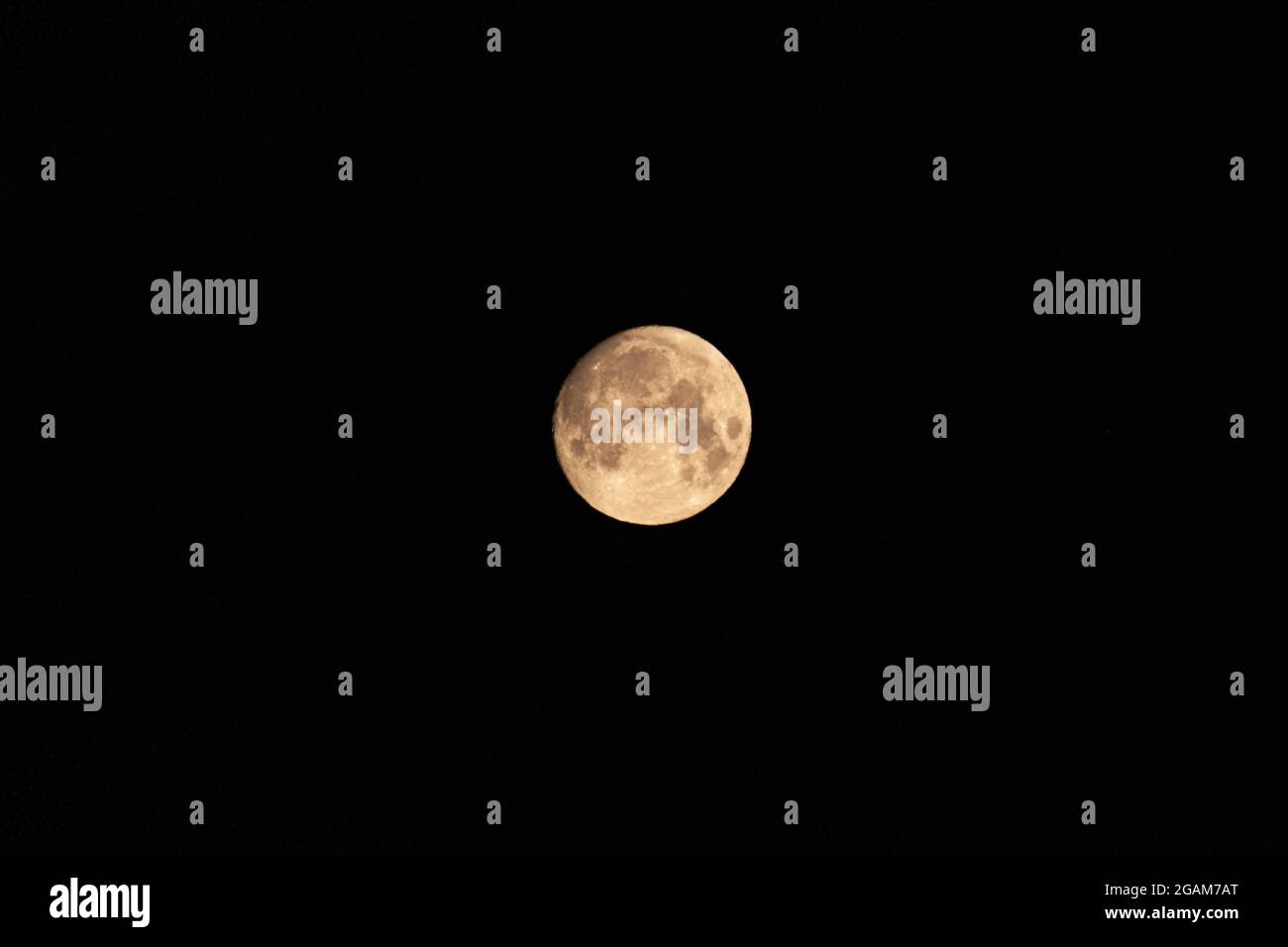 Bright light yellow full moon on dark black night sky. Space object in