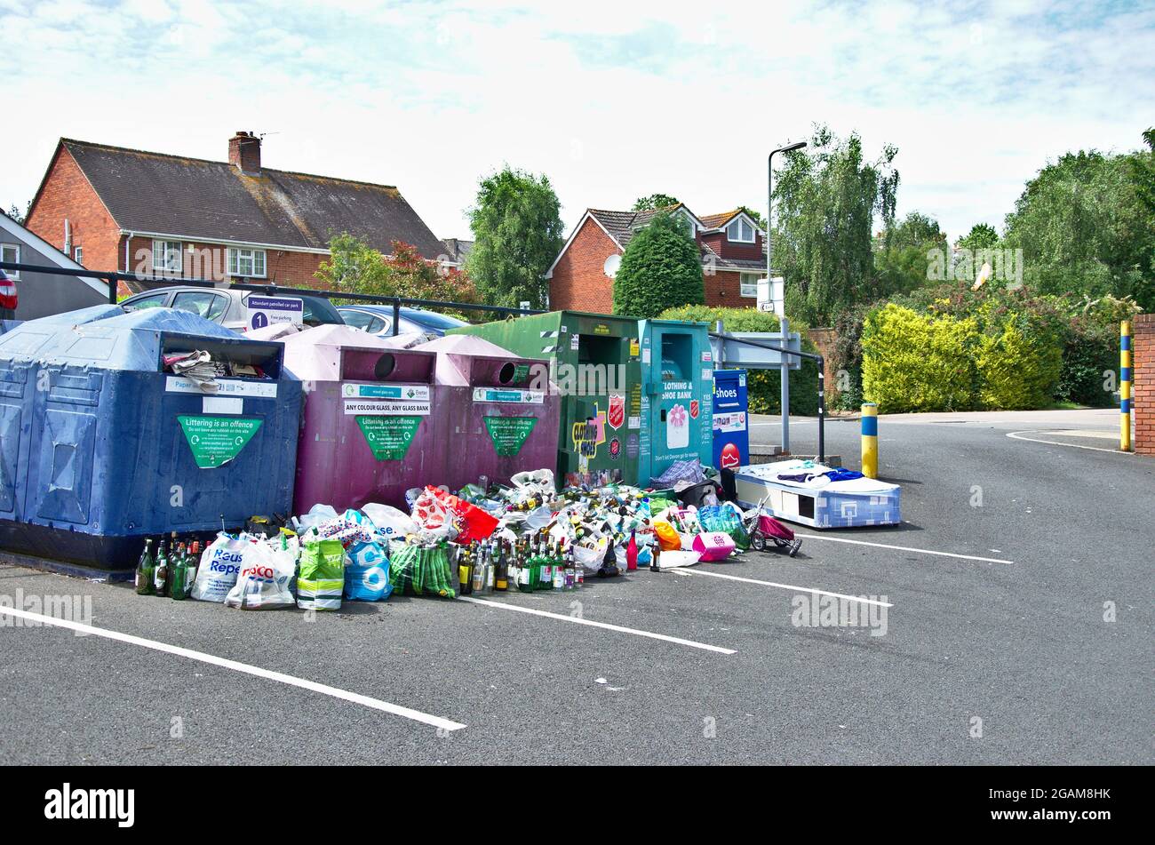 Overflowing recycling collection bins area in a supermarket car park