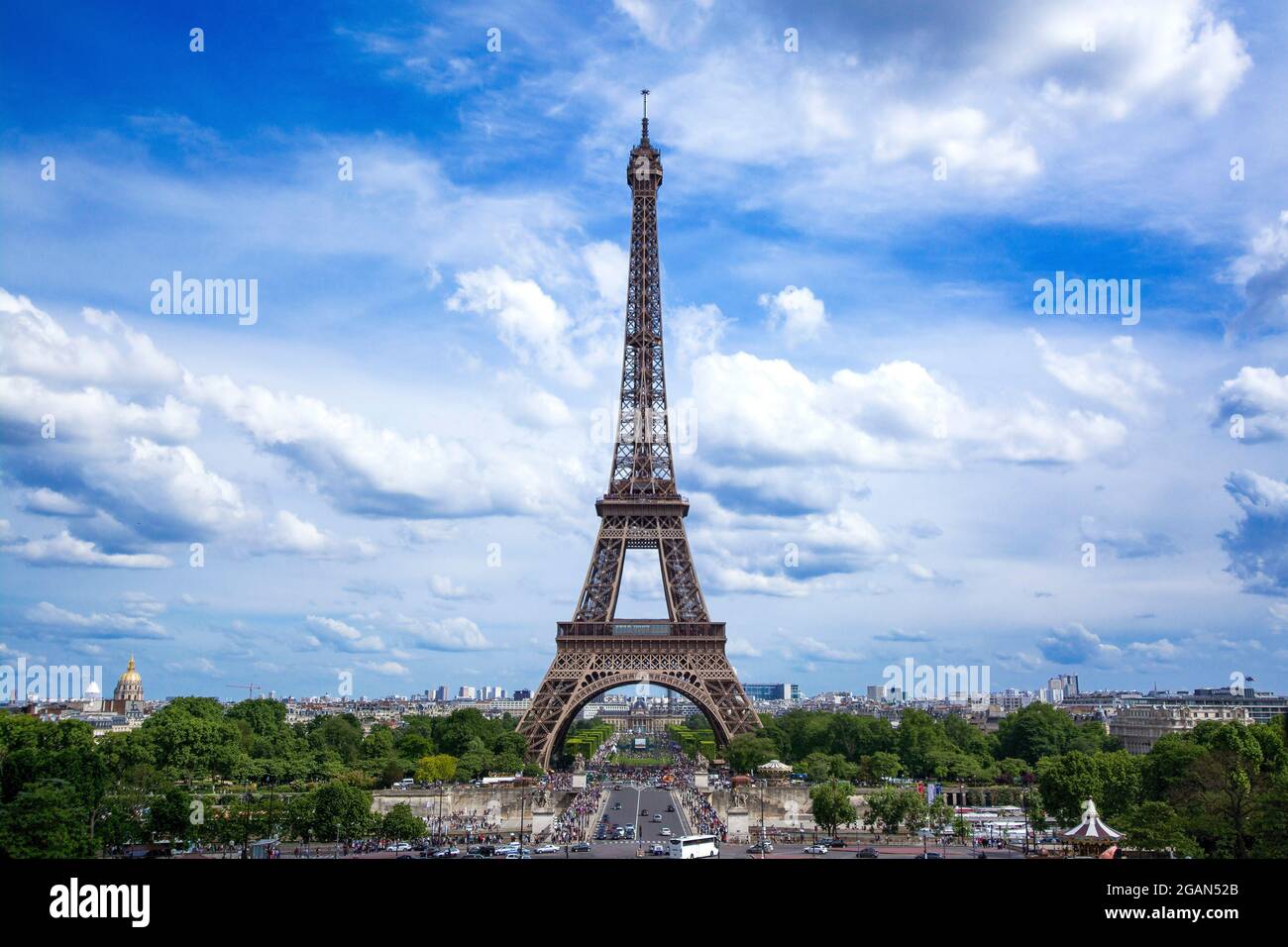 A stunning view of the Eiffel Tower under a blue sky with fluffy clouds in Paris, showcasing its grandeur during the day, France Stock Photo