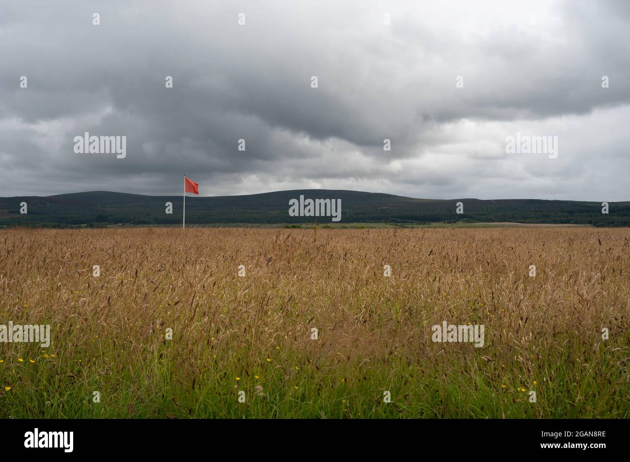 Culloden Moor in the Scottish Highlands with a red flag indicating the position of the English Army in the 1746 battle. Moody skies in the background. Stock Photo