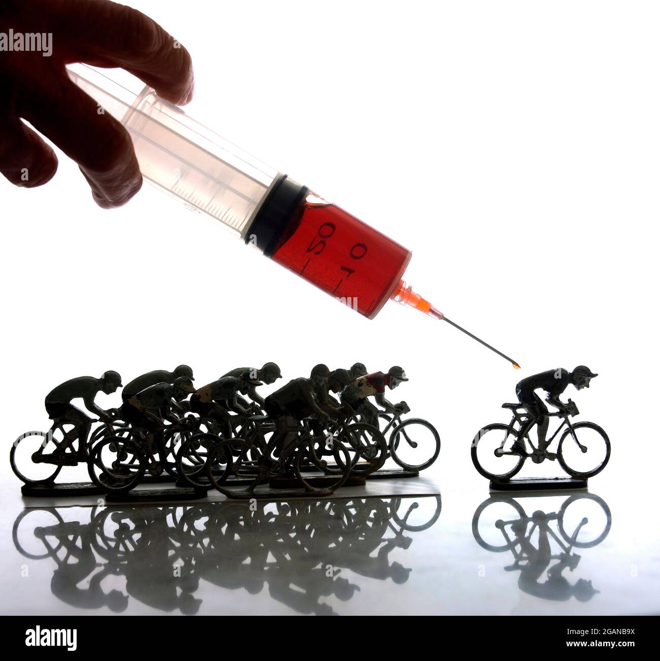 Doping Racing A hand injects a syringe towards miniature cyclists racing on a ...