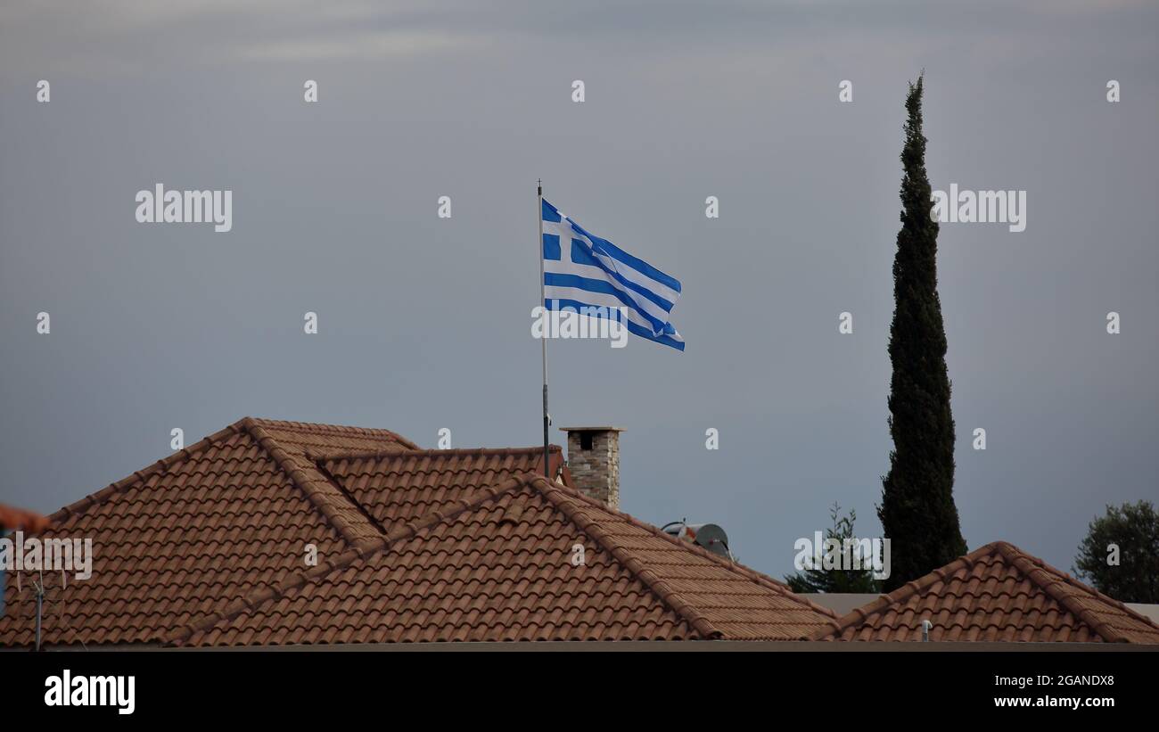 Flag of Grees on flagopel on roof of the house in a town in Cyprus Stock Photo