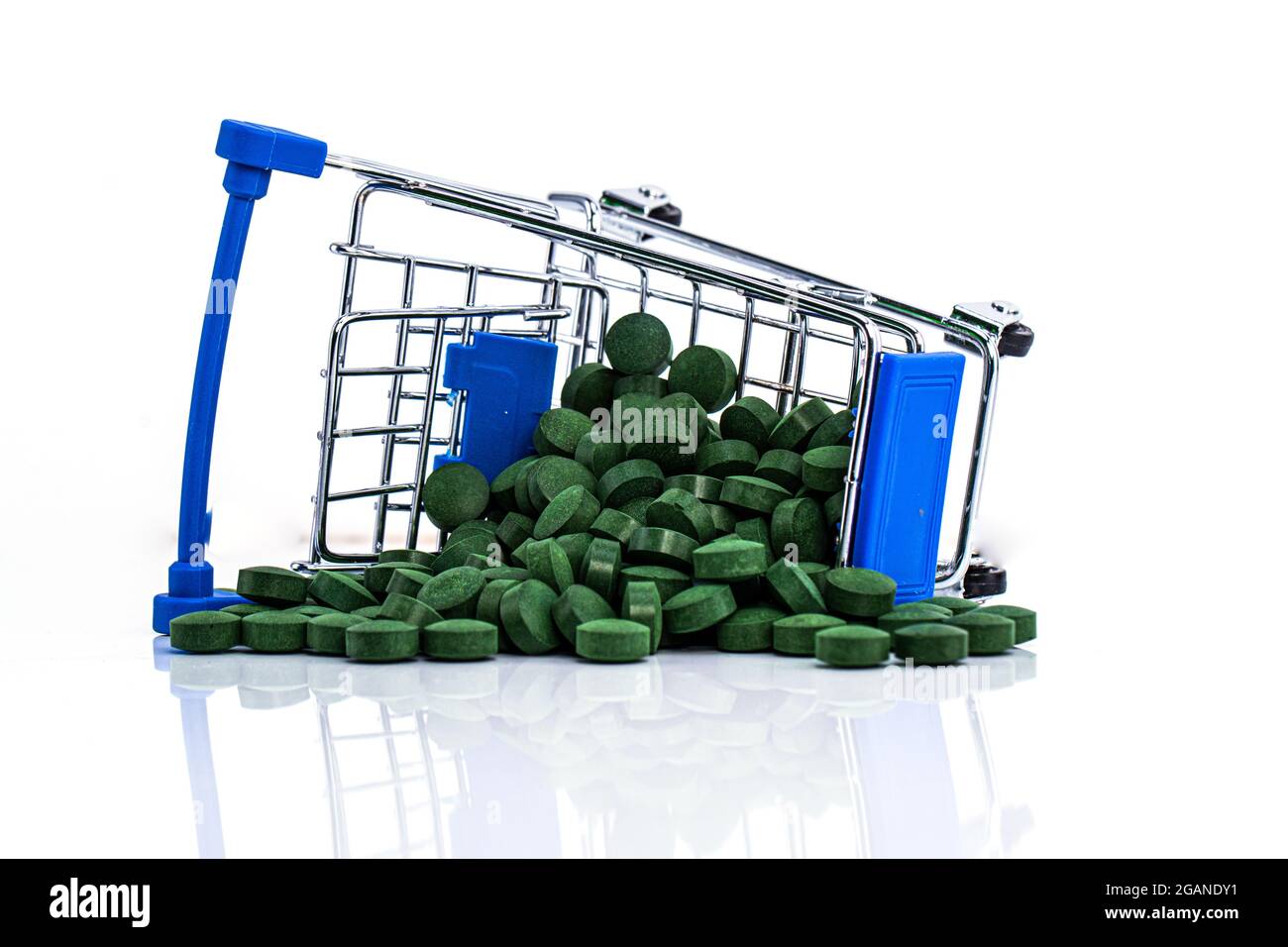 Upside down cart with scattered spirulina pills isolated on white Stock Photo