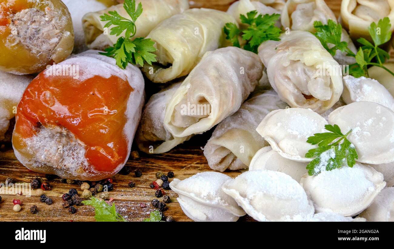 Frozen semi-finished products, stuffed bell peppers, cabbage rolls and dumplings lies on counter in market or on table in the home kitchen. Dolly shot Stock Photo