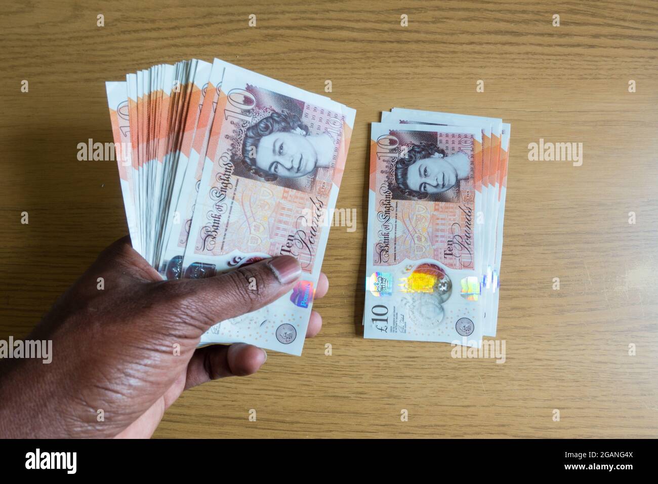 Man counting sterling polymer currency notes on a table Stock Photo