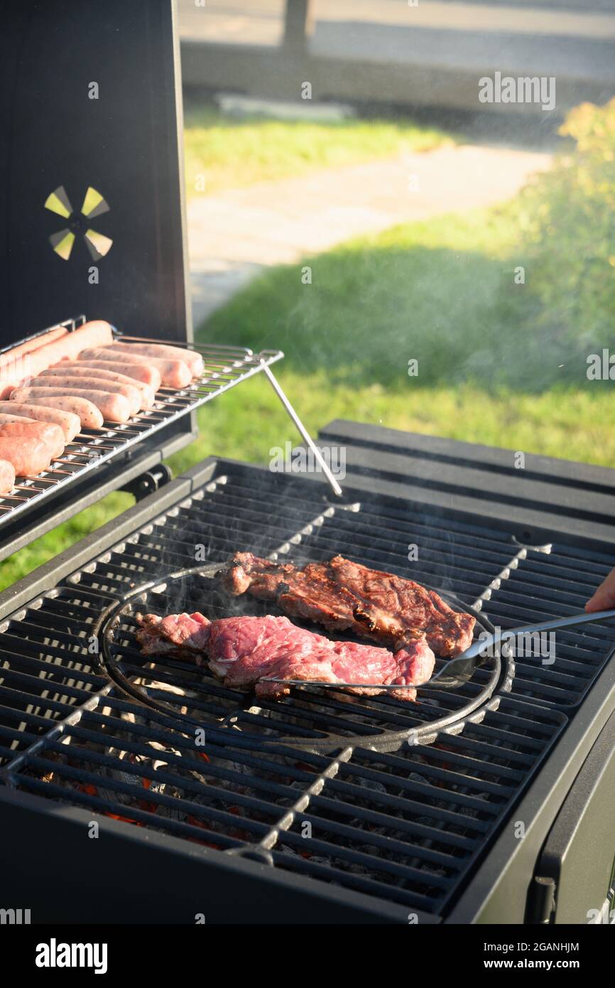 Beef steaks and sausages on grill. Barbecue backyard party. Outdoors. Stock Photo