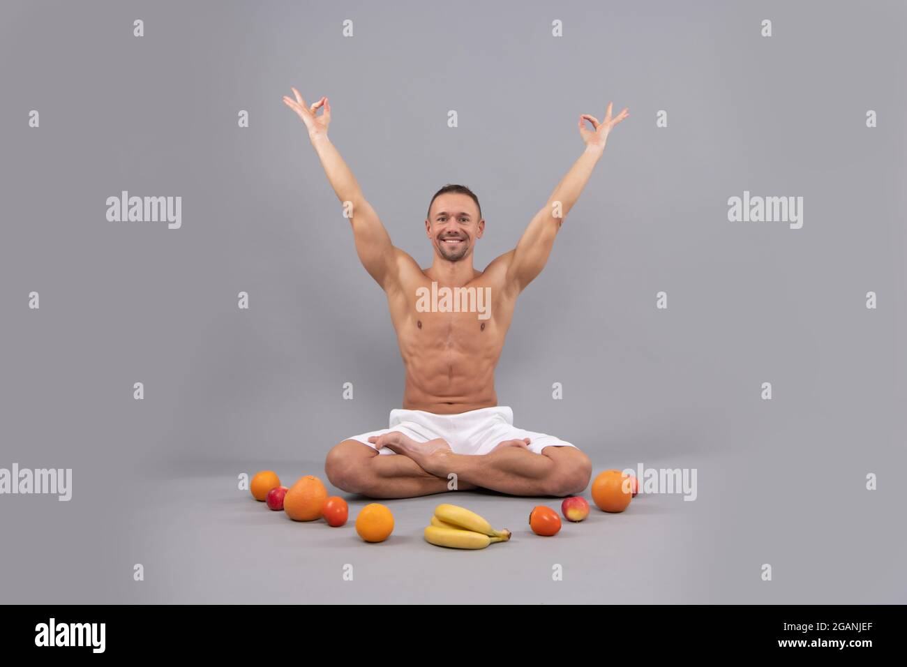 Yogi man sit in lotus position doing mudra with natural organic fruit for vegetarian diet, veganism Stock Photo