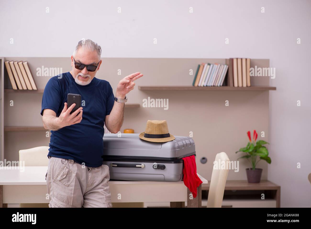 Old male tourist preparing for trip at home Stock Photo