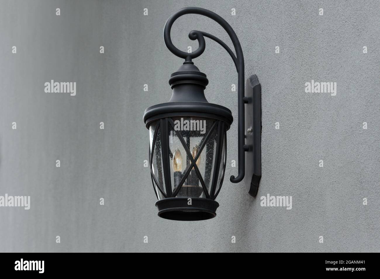 a black decorative outdoor wall sconce on a gray stucco wall with copy space Stock Photo