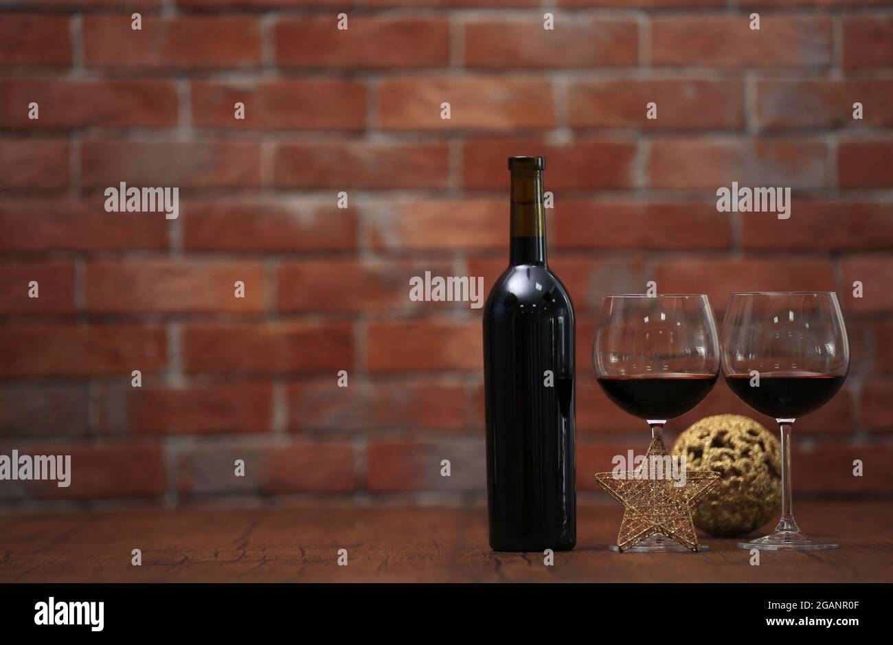 Red wine and Christmas ornaments on wooden table on wall brick