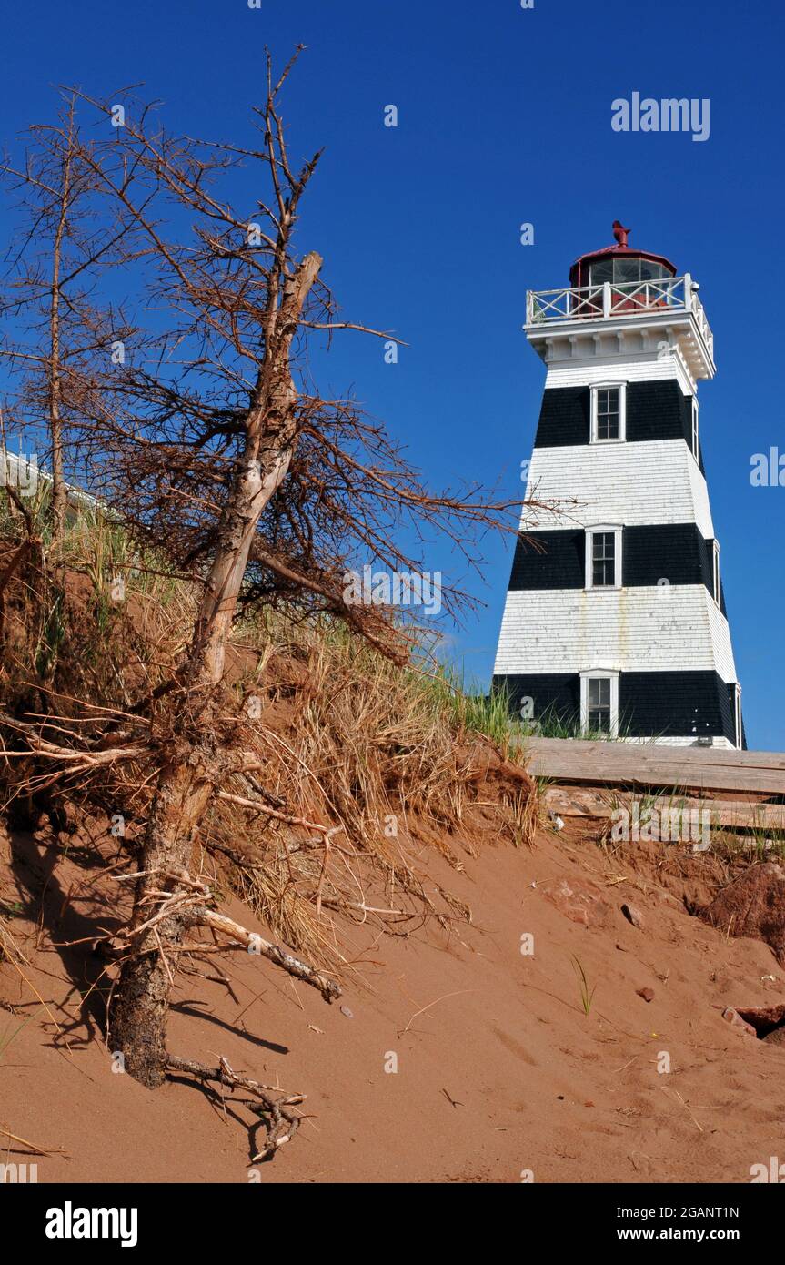 Sand dunes rise near the historic West Point Lighthouse in Prince Edward Island. Built in 1875, the landmark now features an inn and museum. Stock Photo