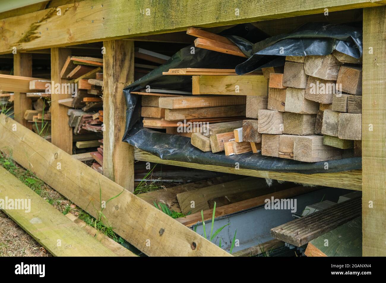 Wood stacked and stored in a garden under a shed Stock Photo Alamy