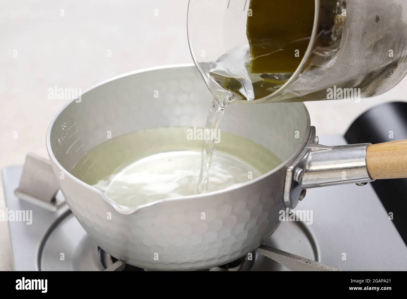 How to make Japanese miso soup.  Put dashi broth in a sauce pan. Stock Photo