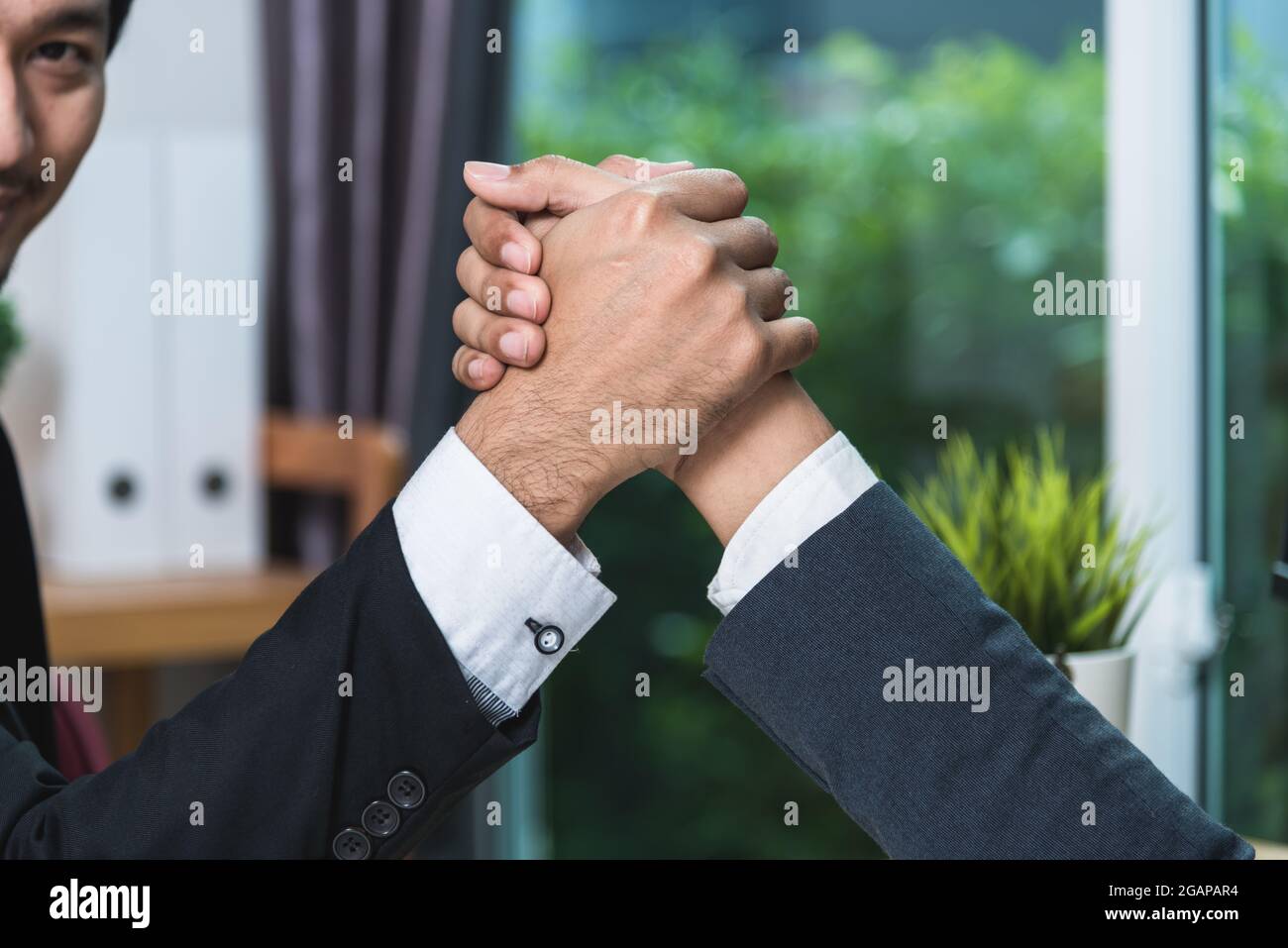 Business man two people sitting opposite at office desk and shaking hands partnership Stock