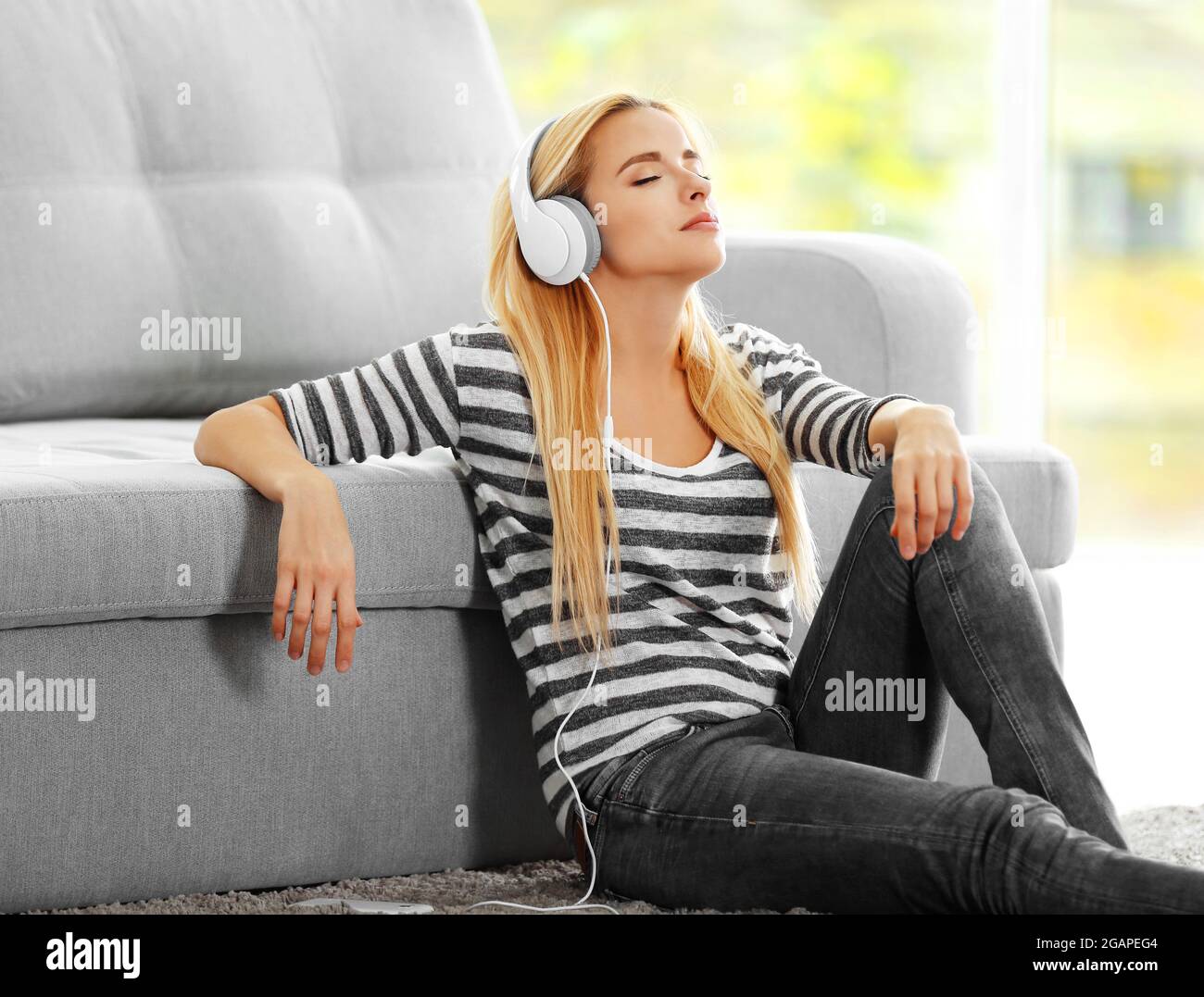 Yong woman sitting on the floor and listening to music Stock Photo - Alamy