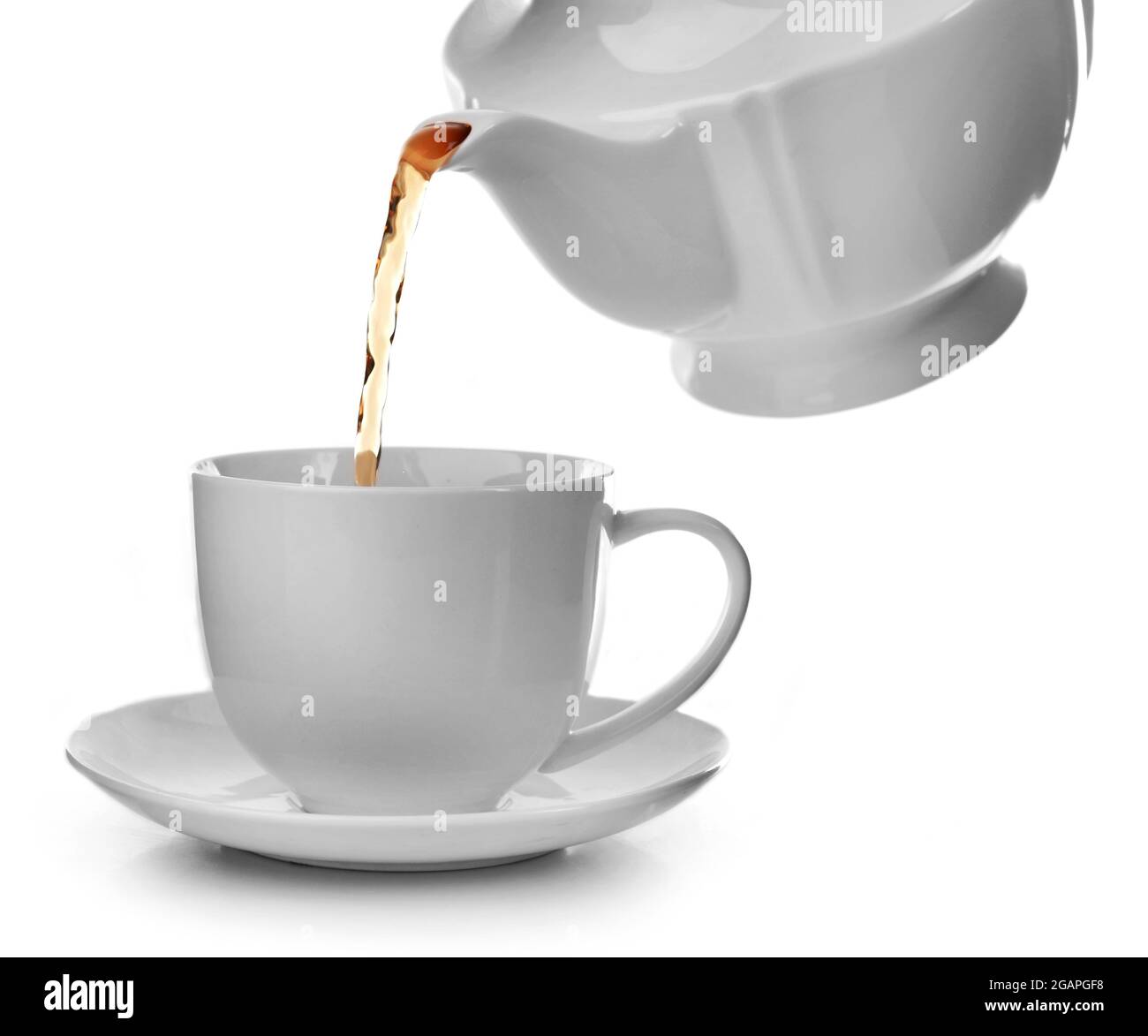 Tea flows from a teapot in a cup isolated on white background Stock