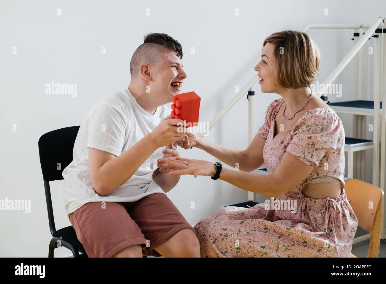 Therapist doing development activities with disabled teenage child. Boy with cerebral palsy having rehabilitation, learning, building. Mental training Stock Photo