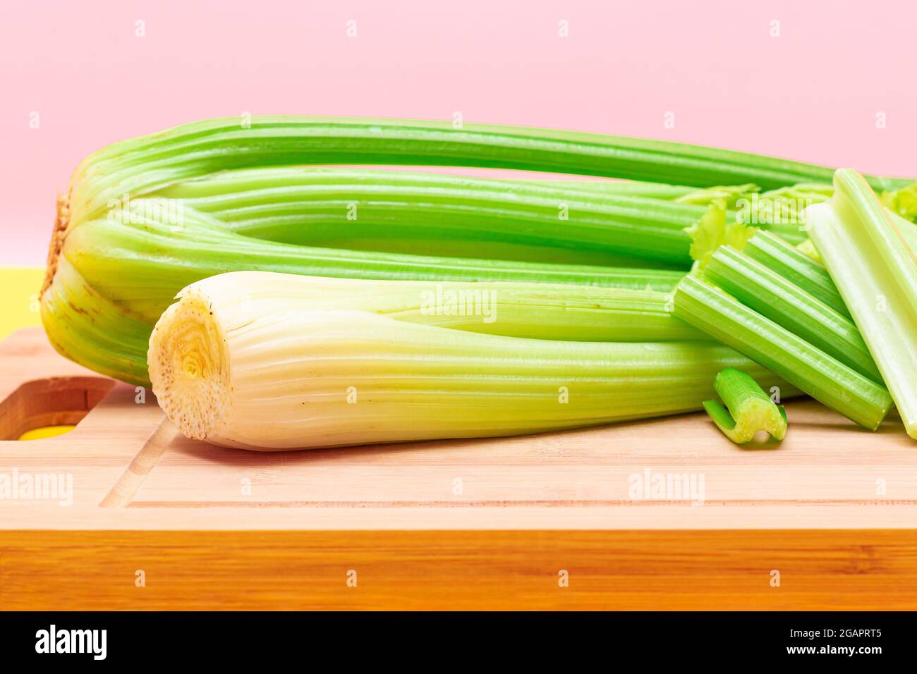 Fresh Celery Stem and Chopped Celery Sticks on Wooden Cutting Board. Vegan and Vegetarian Culture. Raw Food. Healthy Diet with Negative Calorie Content. Slimming Food Stock Photo