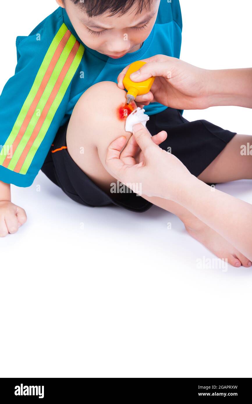 Little asian (thai) boy looking wound his leg, Nurse provides first aid, shoot in studio, Isolated on white background Stock Photo