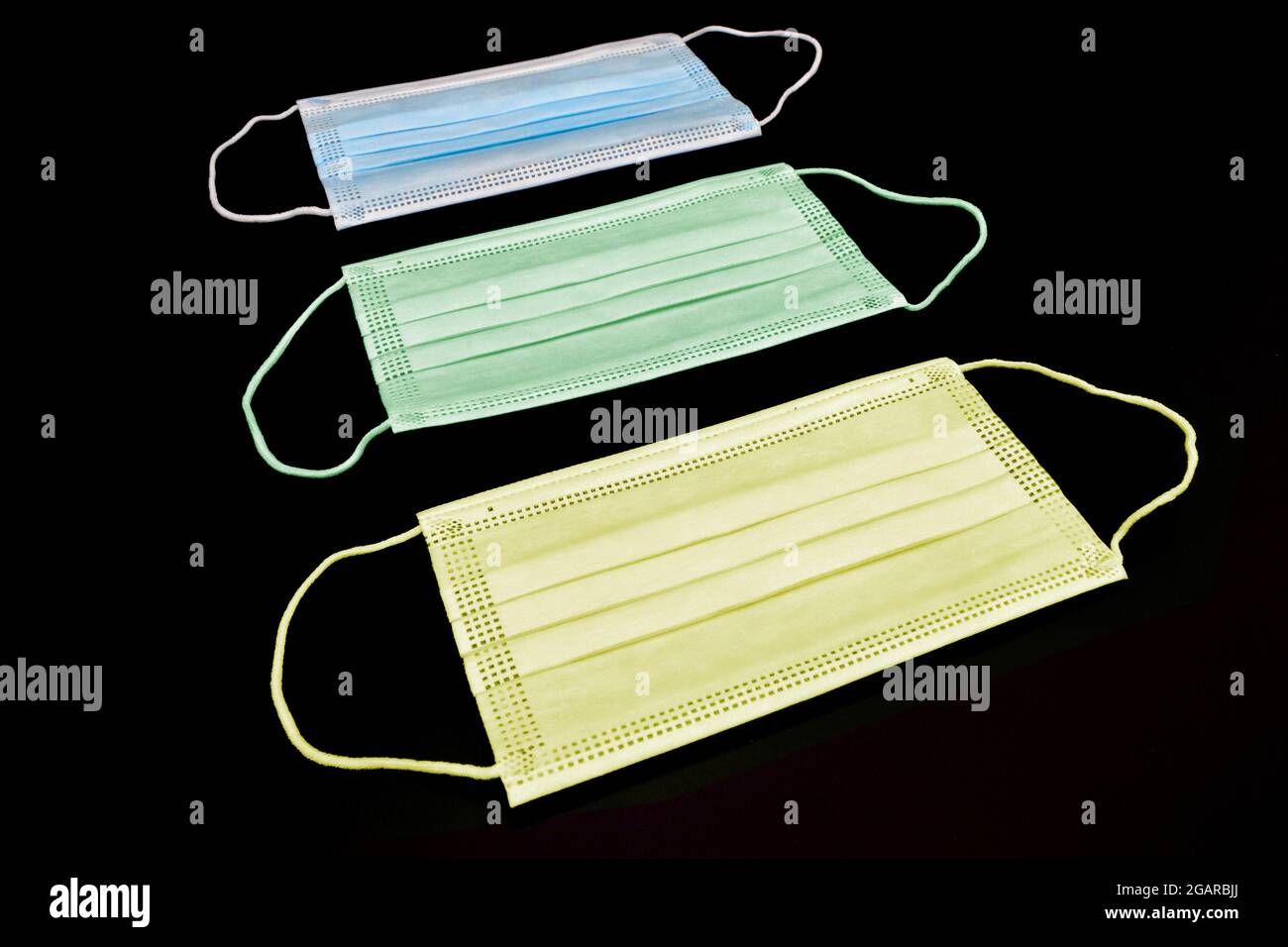 Disposable surgical masks or colorful new medical respirators. COVID-19 prevention. H1N1, H5N1 safety measures. Isolated on black background. Stock Photo