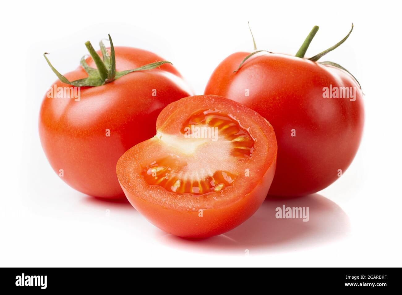 Two fresh red tomatoes and a half tomato isolated on a white background ...