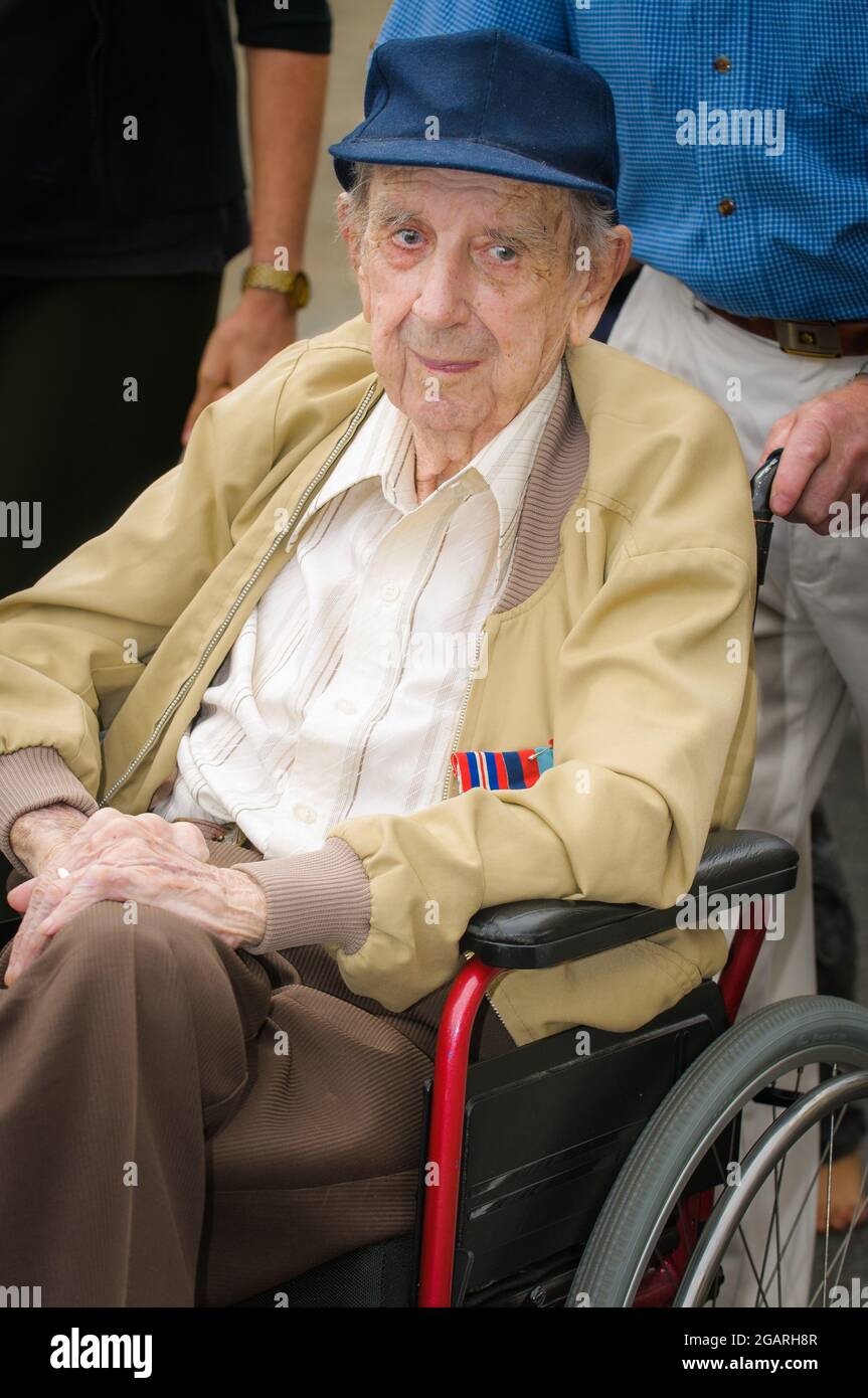 An single veteran 'Digger' seated in a wheel chair staring pensively at the passing ANZAC Day parade at the Cairns Esplanade cenotaph QLD, Australia. Stock Photo