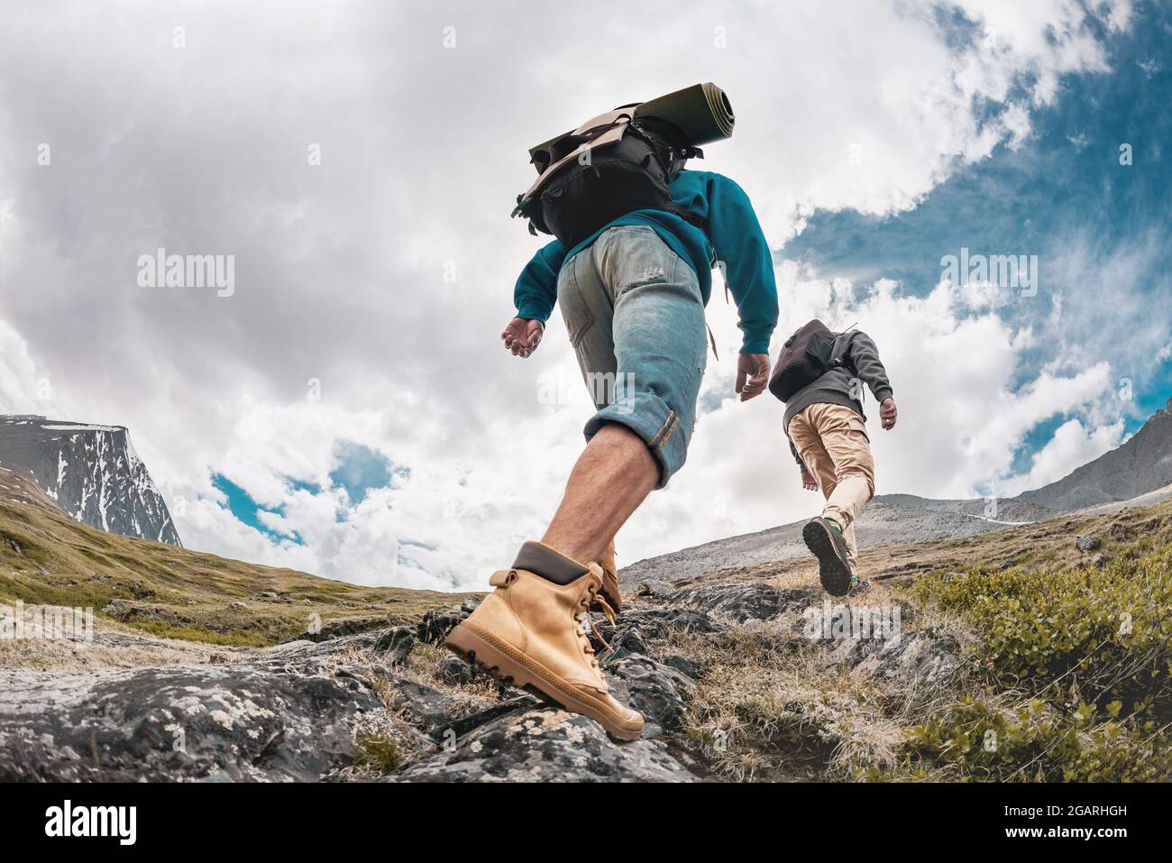 Two hikers with backpacks are walking in mountains. Active tourism concept Stock Photo
