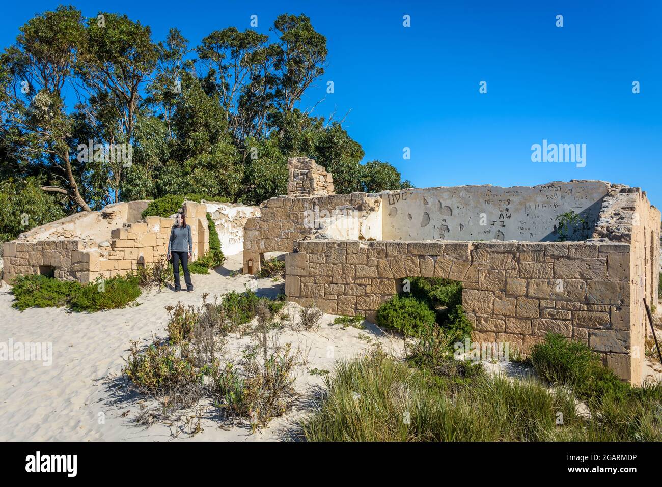 Female traveler stands beside the ruins of the historic Eucla Telegraph Station covered with shifting windblown sand. Nullabor Plain Western Australia Stock Photo