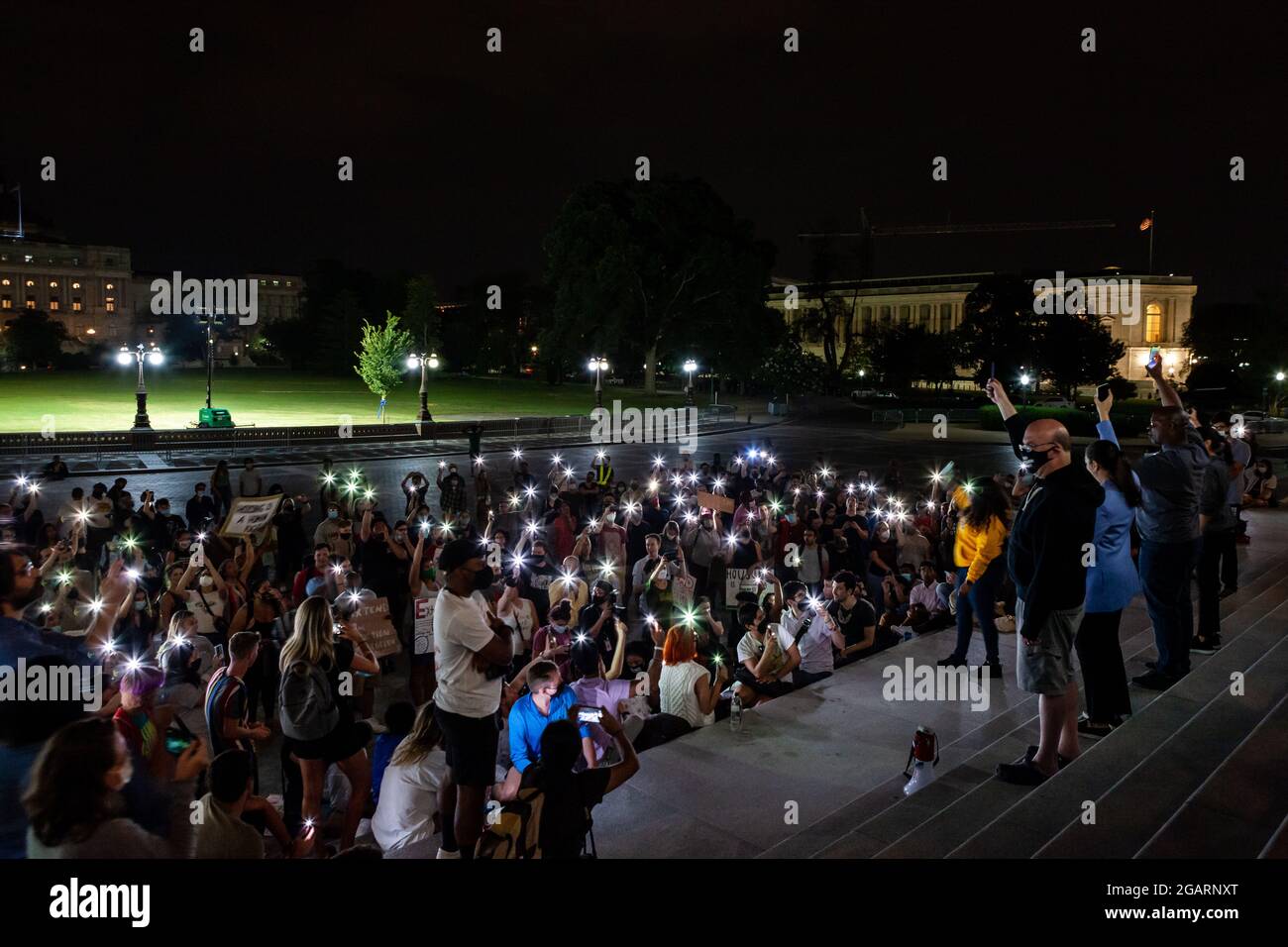Washington, DC, USA. 1st Aug, 2021. Pictured: Protesters at a midnight rally on the steps of the Capitol hold their phones in the air at Congresswoman Cori Bush's (D-MO) request, in a moment of silence to remember those who have been lost due to homelessness and the pandemic. Representatives Jim McGovern (D-MA), Sara Jacobs (D-CA), Jamaal Bowman (D-NY), and Alexandria Ocasio-Cortez (D-NY) stand behind her with phones raised. Congresswoman Bush called the rally to protest the expiration of the eviction moratorium at midnight August 1. Credit: Allison Bailey/Alamy Live News Stock Photo