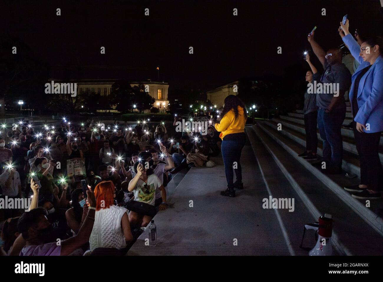 Washington, DC, USA. 1st Aug, 2021. Pictured: Protesters at a midnight rally on the steps of the Capitol hold their phones in the air at Congresswoman Cori Bush's (D-MO) request, in a moment of silence to remember those who have been lost due to homelessness and the pandemic. Representatives Alexandria Ocasio-Cortez (D-NY), Jamaal Bowman (D-NY), and Sara Jacobs (D-CA) stand behind her. Congresswoman Bush called the rally to protest the expiration of the eviction moratorium at midnight August 1. Credit: Allison Bailey/Alamy Live News Stock Photo