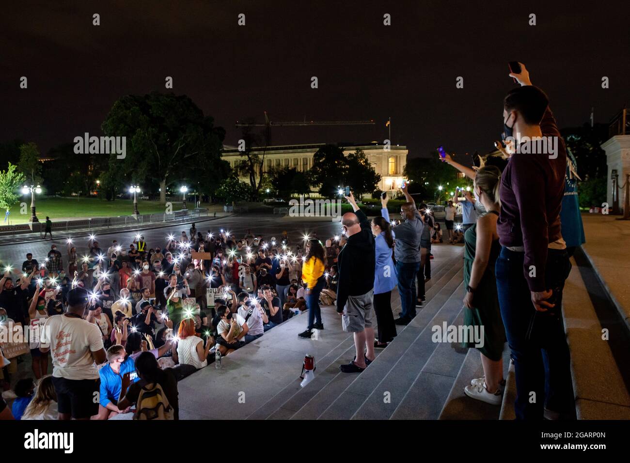 Washington, DC, USA. 1st Aug, 2021. Pictured: Protesters at a midnight rally on the steps of the Capitol hold their phones in the air at Congresswoman Cori Bush's (D-MO) request, in a moment of silence to remember those who have been lost due to homelessness and the pandemic. Representatives Jim McGovern (D-MA), Sara Jacobs (D-CA), Jamaal Bowman (D-NY), and Alexandria Ocasio-Cortez (D-NY) stand behind her with phones raised. Congresswoman Bush called the rally to protest the expiration of the eviction moratorium at midnight August 1. Credit: Allison Bailey/Alamy Live News Stock Photo