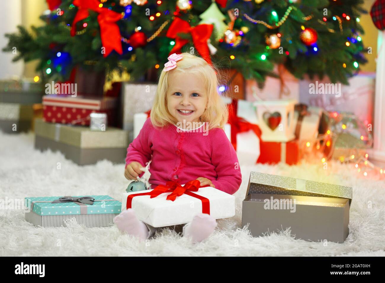 Funny girl with gift boxes and Christmas tree on background Stock Photo