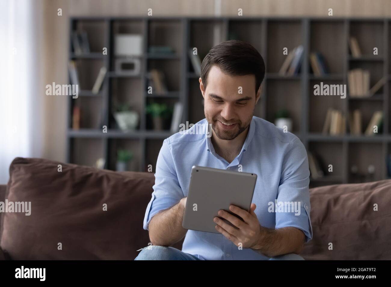 Focused millennial guy student enjoy using digital tablet at home Stock Photo