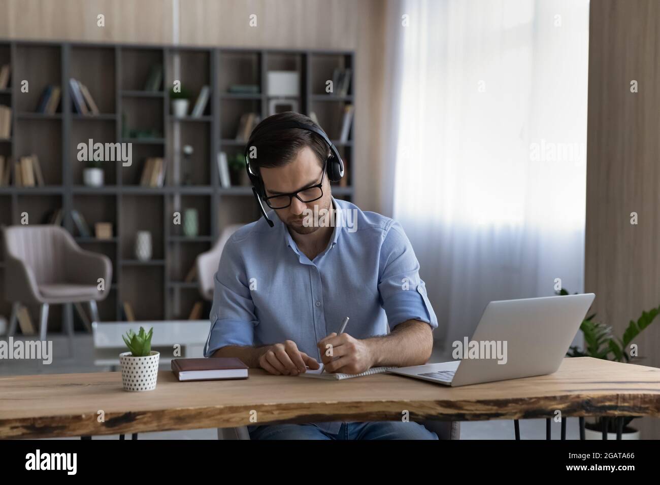 Focused young man student wear headphones handwriting before pc screen Stock Photo