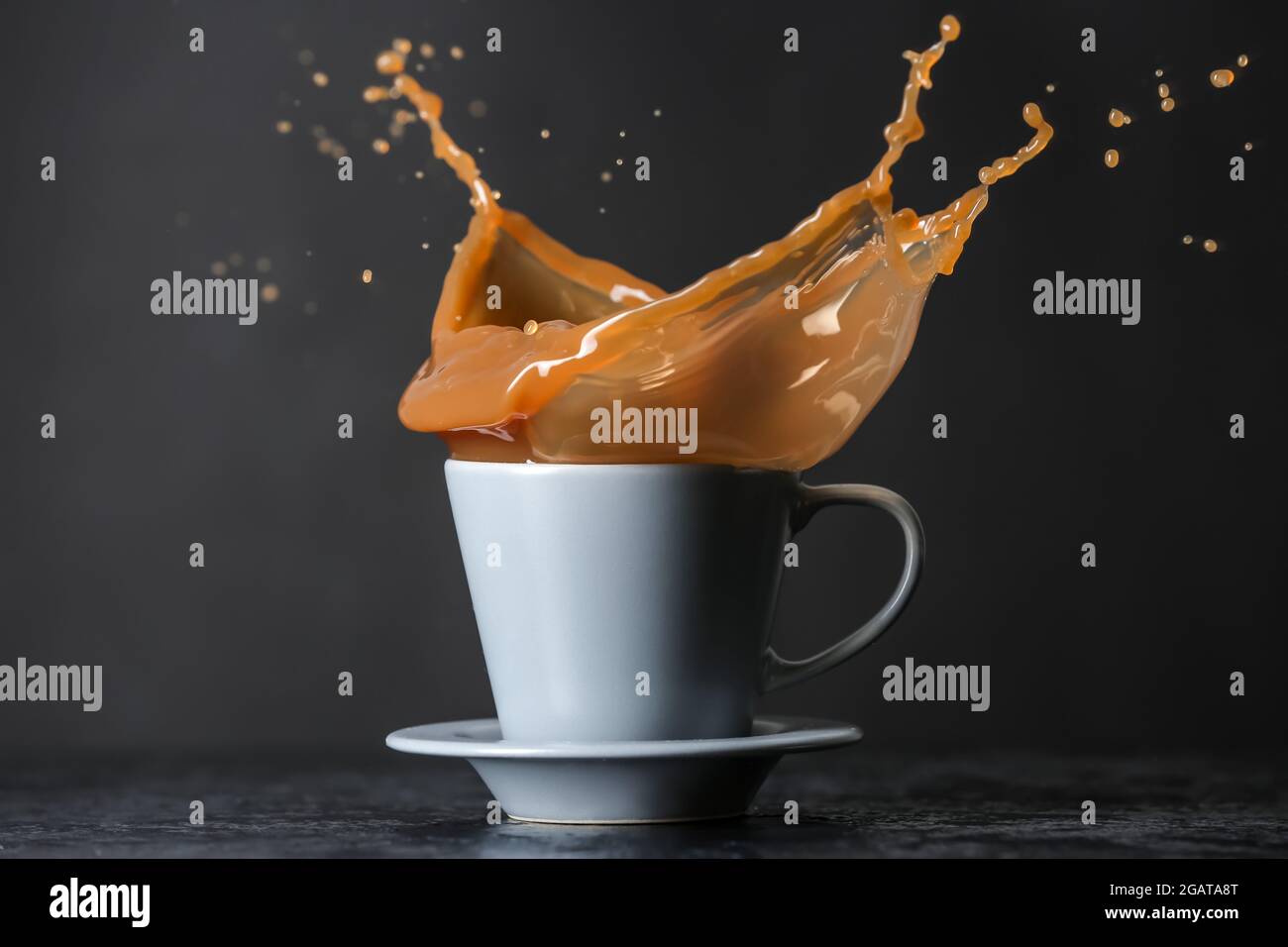 Cup with coffee splash on dark background Stock Photo - Alamy