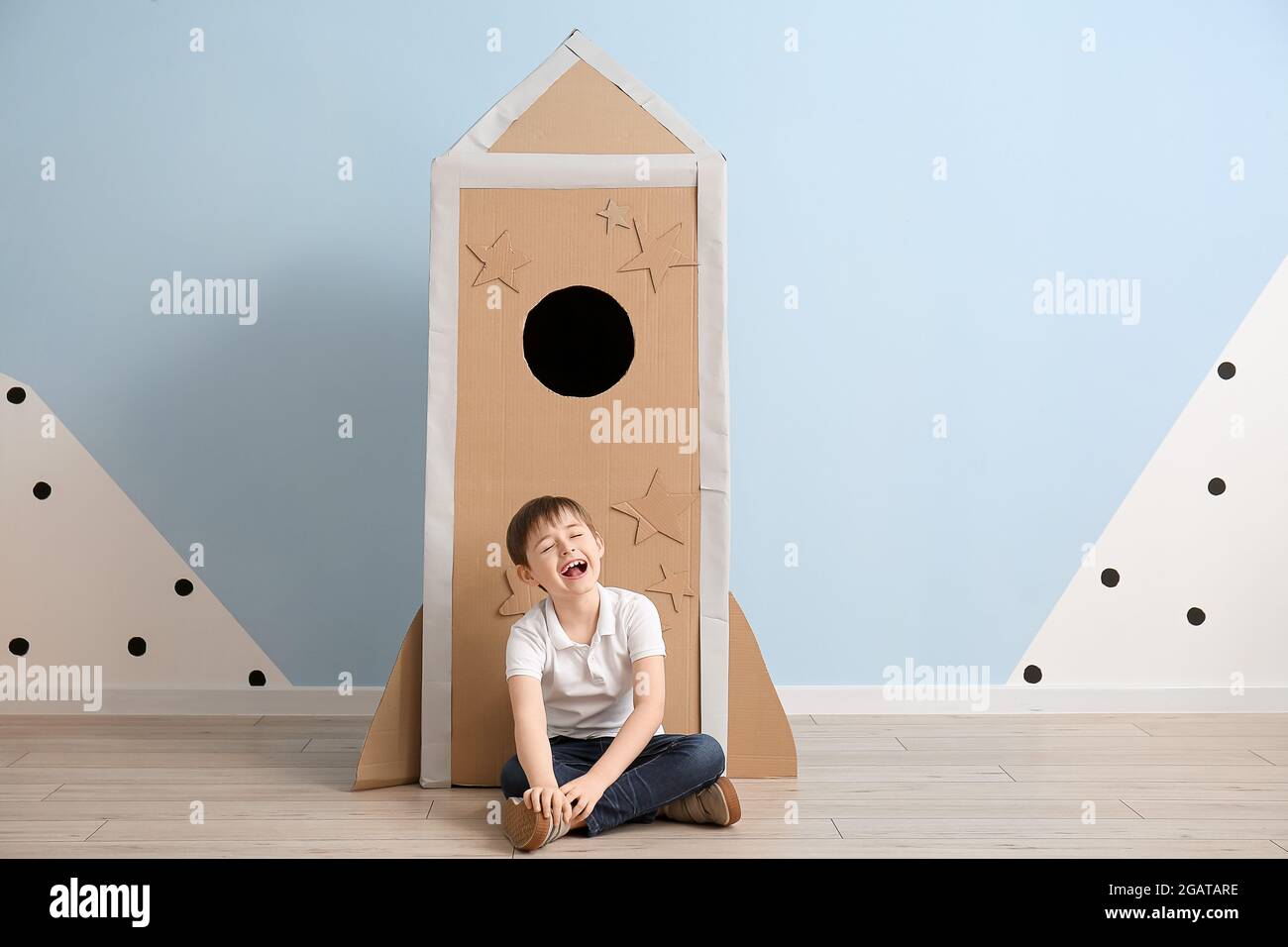 Cute little boy playing with cardboard rocket near color wall Stock ...