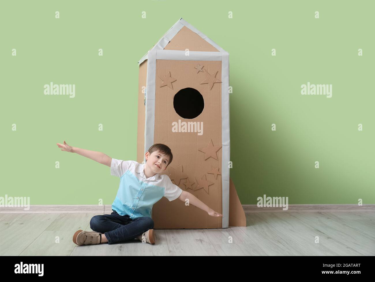 Cute little boy playing with cardboard rocket near color wall Stock ...