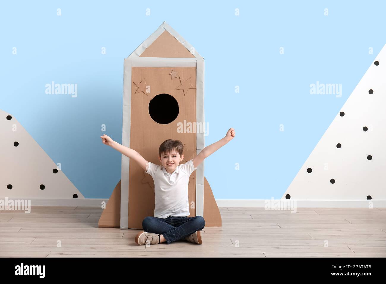 Cute little boy playing with cardboard rocket near color wall Stock ...