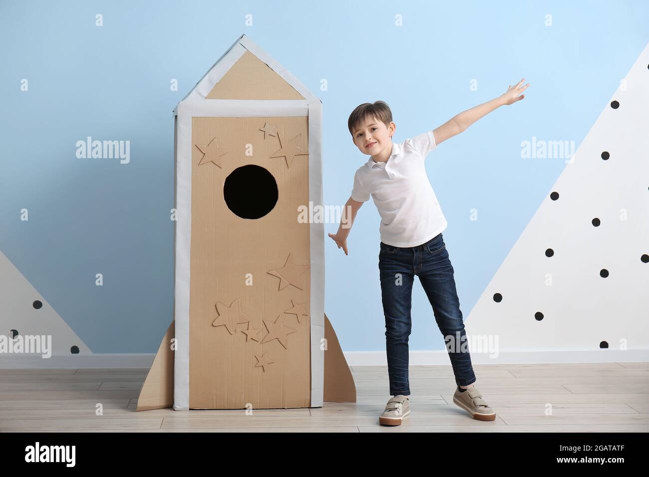 Cute little boy playing with cardboard rocket near color wall Stock ...