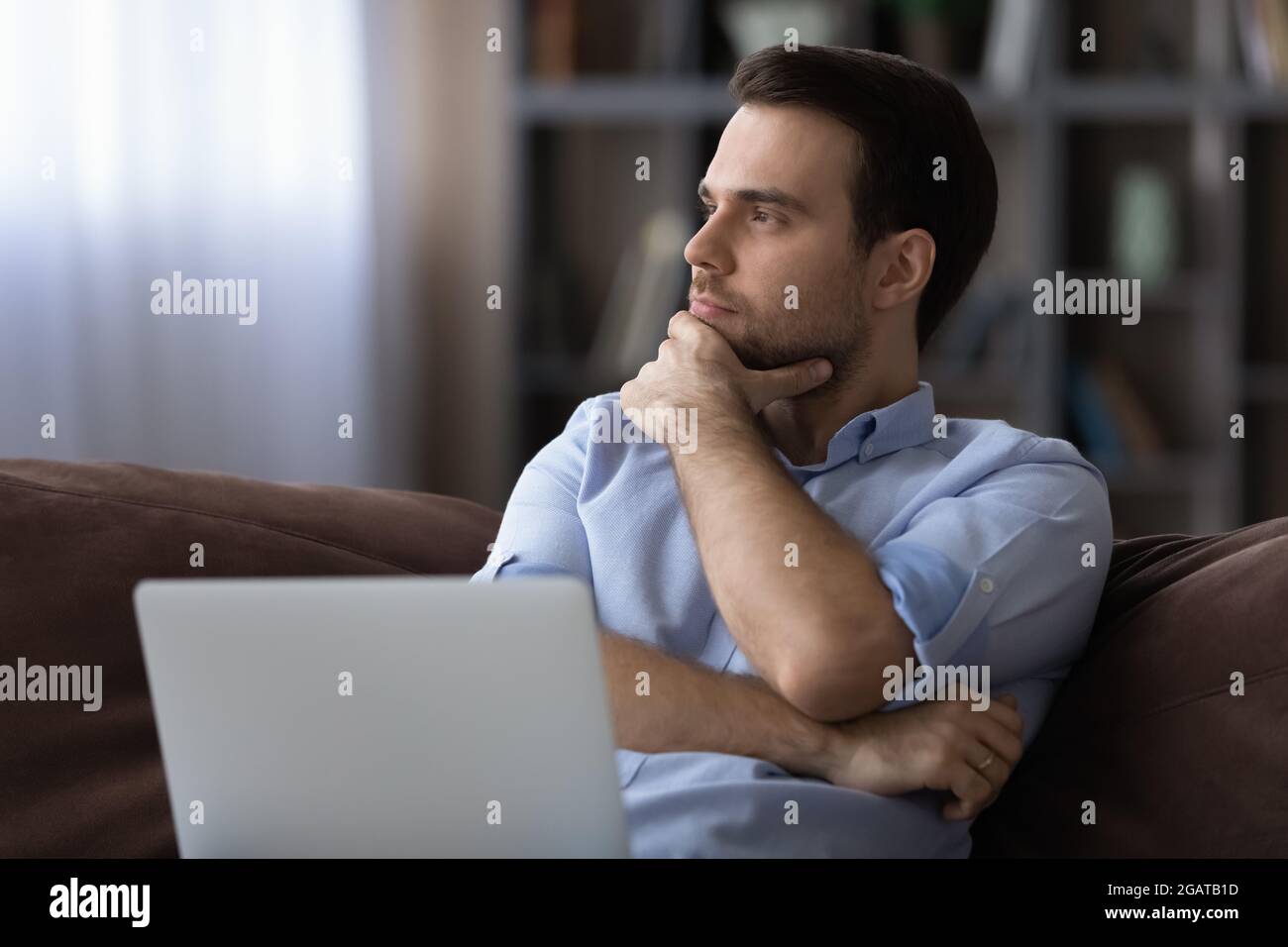 Contemplative young man distracted from laptop ponder on project solution Stock Photo