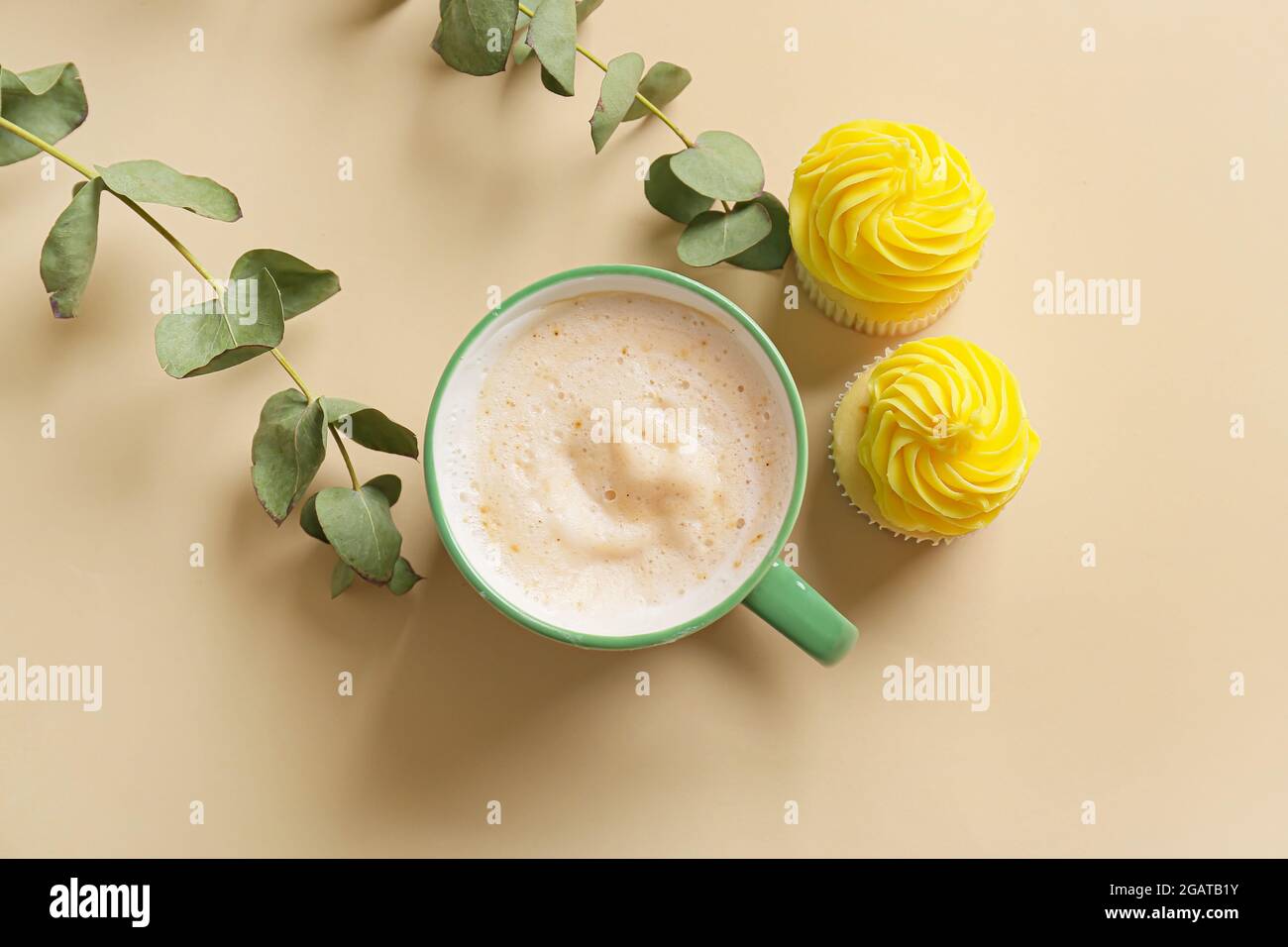 Cup of coffee with cupcakes and plant branches on color background Stock Photo