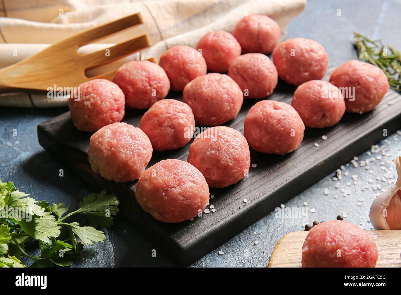 Wooden board with raw cutlets made of fresh forcemeat on color